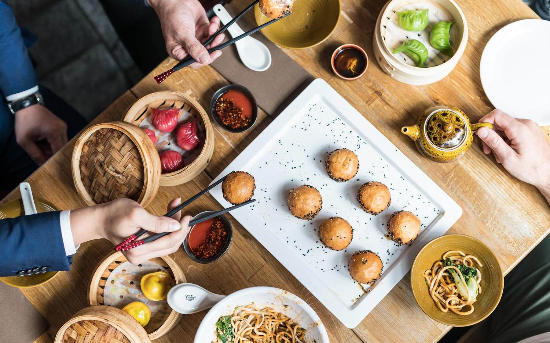 Aerial photograph of a dining table with people sharing food.